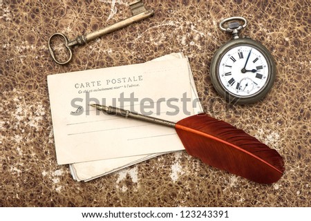 nostalgic vintage background with old post cards, clock, key and feather pen