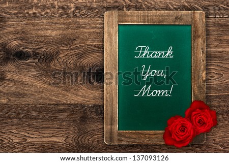 vintage green blackboard with rustic frame and red roses on wooden background. Sample Text Thank You, Mom!