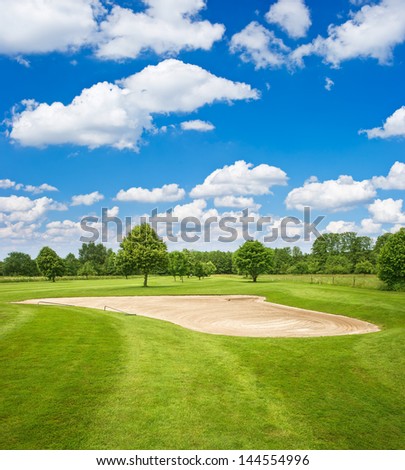 green golf course and blue cloudy sky. european field landscape