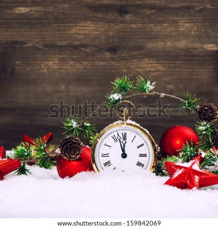 christmas decoration red stars, baubles and antique golden clock in snow over wooden background