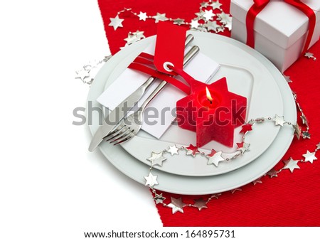 festive christmas table place setting decoration in red and silver. candle light dinner