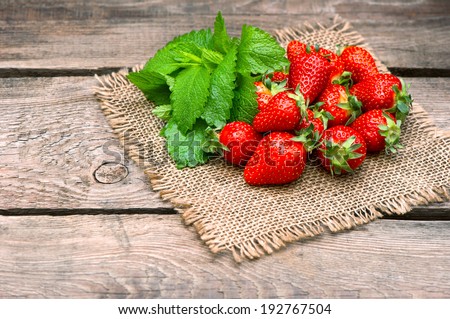 strawberries with fresh mint leaves on wooden background. country style picture. selective focus