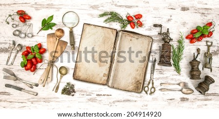 Old cookbook with vegetables, herbs and vintage kitchen utensils. Retro style toned picture