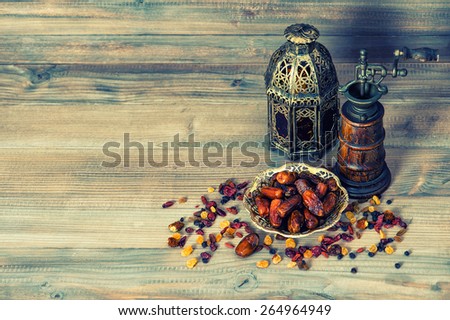 Raisins and dates on wooden background. Still life with vintage oriental lantern. Retro style toned picture