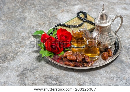 Tea, dates fruits, red rose flower, holy book quran and rosary. Islamic holidays decoration. Ramadan kareem. Eid mubarak. Oriental hospitality concept. Vintage style toned picture