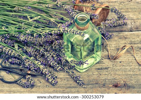 Herbal lavender oil with fresh flowers on wooden background. Vintage style toned photo