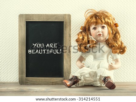 Vintage doll and chalkboard with sample text You are beautiful! Retro style toned