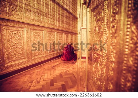 MYANMAR - FEBRUARY 9: Unidentified Monk in Red suit make meditation in big golden room at Botataung pagoda on February 09, 2014 in Yangon, Myanmar