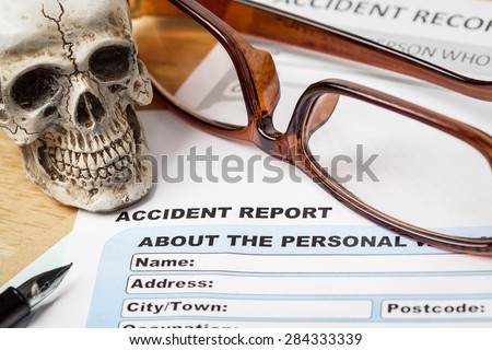 Accident report application form and human skull on brown envelope and eyeglass, business insurance and risk concept; document is mock-up