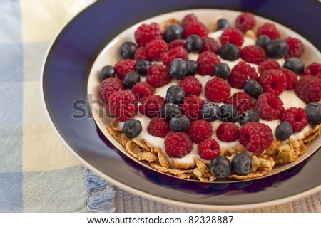 Blue bowl with cereal, yogurt, raspberries and blueberries