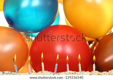 seven lit birthday candles in front of balloons