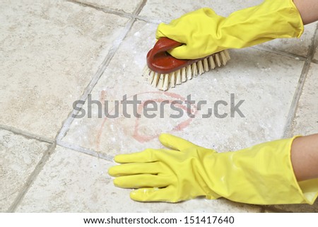 hands in rubber gloves scrubbing the tiles