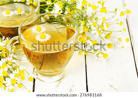 cup of chamomile tea with chamomile flowers on wooden planks