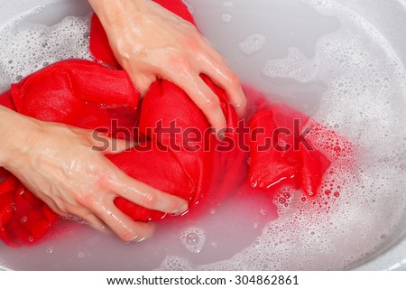woman washing delicate clothes by hands in plastic tub