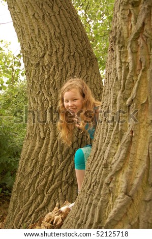 Portrait of young girl with red hair playing around trees