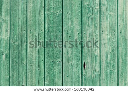 Background texture of old green painted weathered wooden planks forming an exterior cladding on a wall of a building or a fence