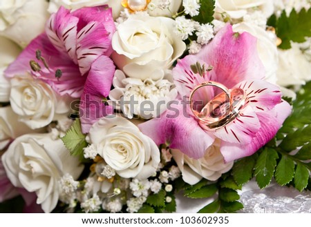 Gold wedding rings of the groom and the bride on a bunch of flowers.