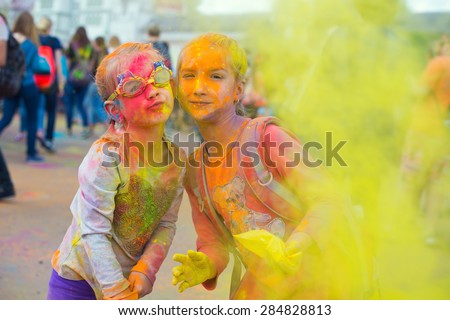 Two cute european sisters child girls celebrate Indian holi festival with colorful paint powder on faces and body