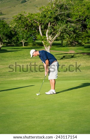 Man on putting golf putting green about to strike golf ball with