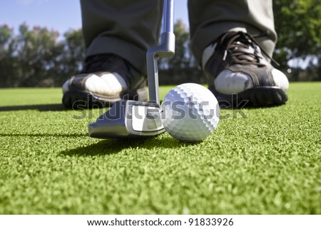 Close up of golfer setting up for a putt on the putting green.