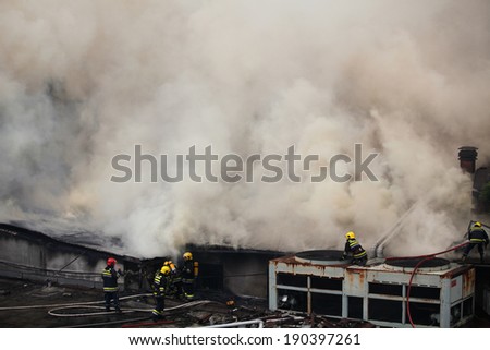 BELGRADE, SERBIA - MAY 25, 2012: A firefighter sprays chemical retardant on smoldering hay bales following a barn fire that called multiple alarms at 3:00PM in the morning.