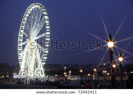 A giant wheel attraction in a park in Paris by night