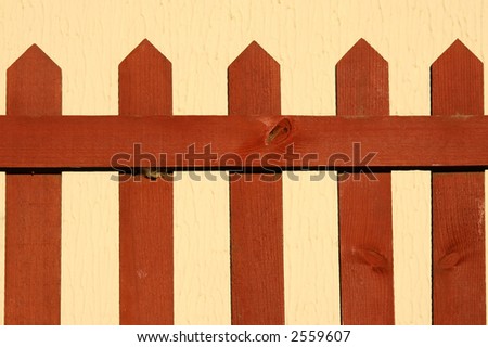 A dark wood stained fence with a cream colored background.