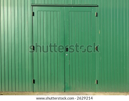 Green doors and wood wall of a storage room.