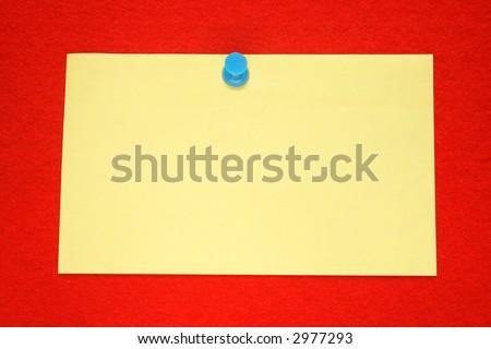 A yellow note held on a red felt notice board with a blue push-pin.