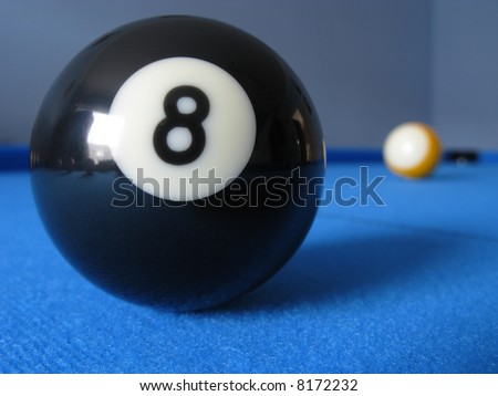 8 ball on a pool table with the 9 ball in the distance.