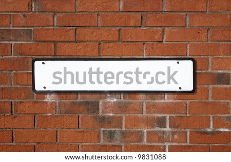 Blank white British street sign on a red brick wall.