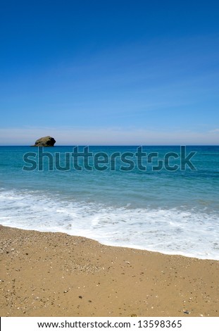 Gull rock island, the beach, blue summer sky and sea in Portreath, Cornwall UK.