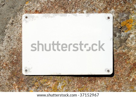 Old blank sign on a stone wall ready for text.