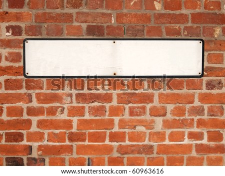 Old blank white British street sign on a red brick wall.