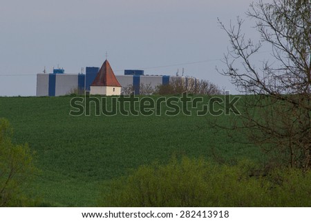 The church of Naabsiegenhofen with an old industrial building called Bayernwerk behind, spring landscape next to Schwandorf in Bavaria