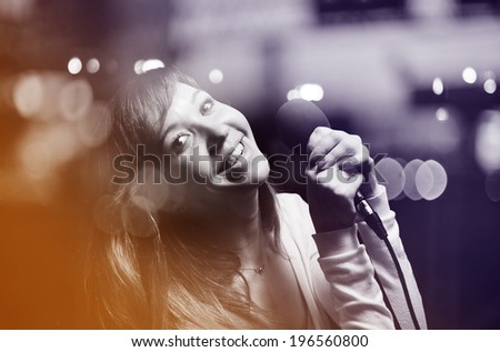 Beautiful girl with a microphone at a karaoke bar.
