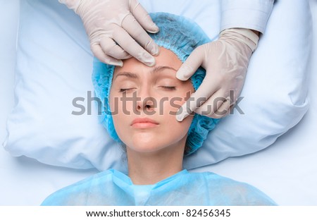 Beautician touch and draw correction lines on woman face