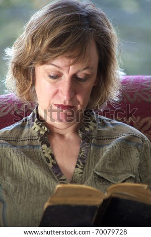 Close up photo of baby boomer woman reading a book with back-lighting