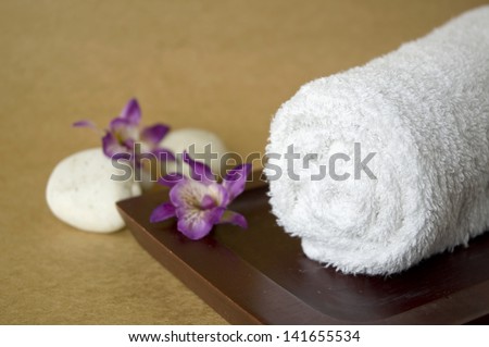 roll of white towel put on wooden tray with orchid