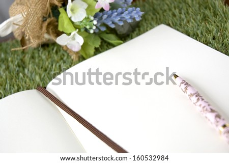 open blank paper page with pen on grass