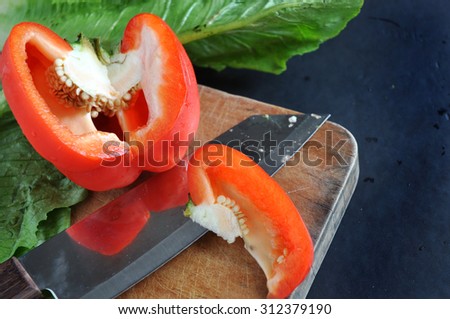 cutting red bell pepper on wooden cutting board