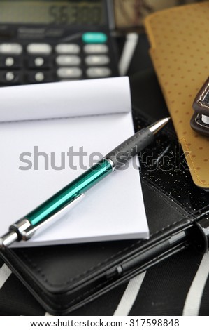 pen and blank white paper put on black note book with calculator on background