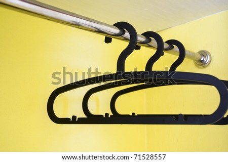 black clothes hanger on a clothes rail with yellow background.