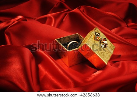 Gold boxes with a wedding ring on red silk