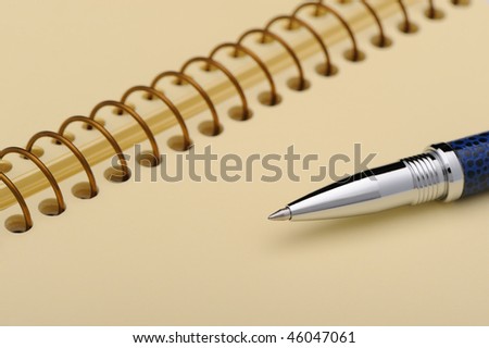 Pen and a notebook on a spiral with a yellow paper. Photo closeup