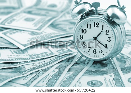 Time - money. Business concept. Analog hours on a heap of paper dollars. Blue tone