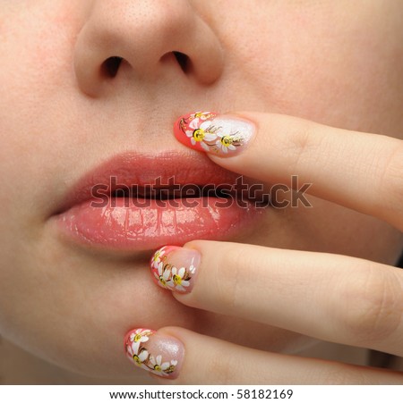 Female face close up and nail art. Figure of camomiles on nails