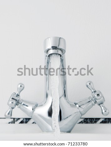 Water tap with a water stream. A bathroom with a white tile