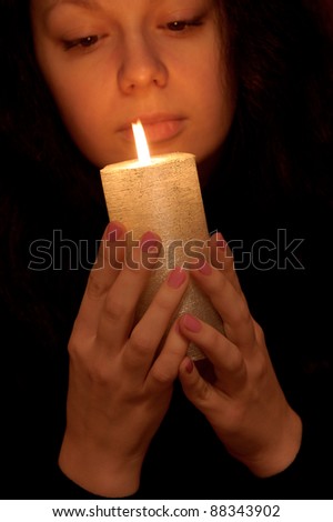 The woman with burning candle. Selective focus on a candle