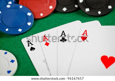 Four aces and poker chips on a green felt
